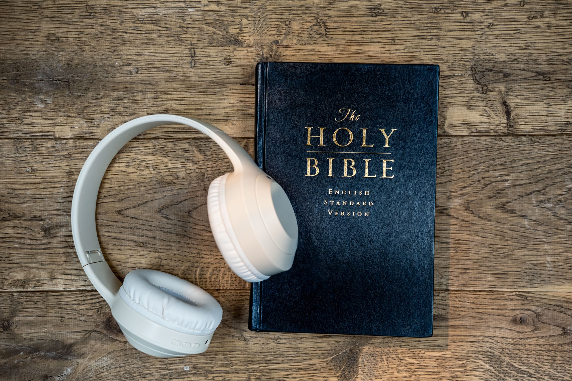 Holy Bible and Headphones on Rustic Wooden Table